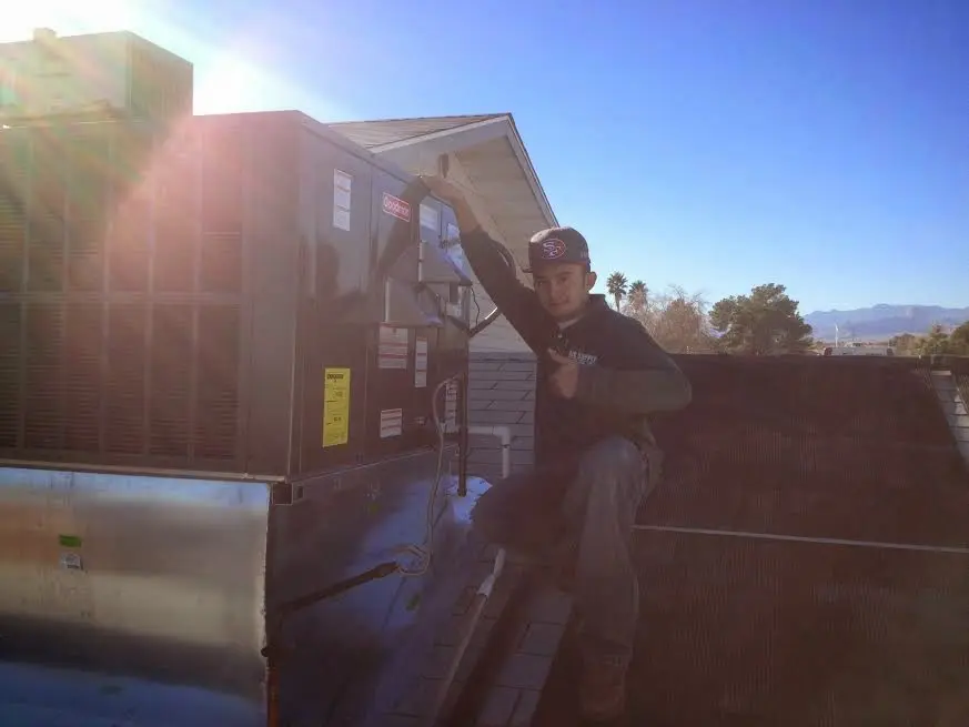 HVAC technician performing Air Duct Repair on a rooftop unit in Enterprise