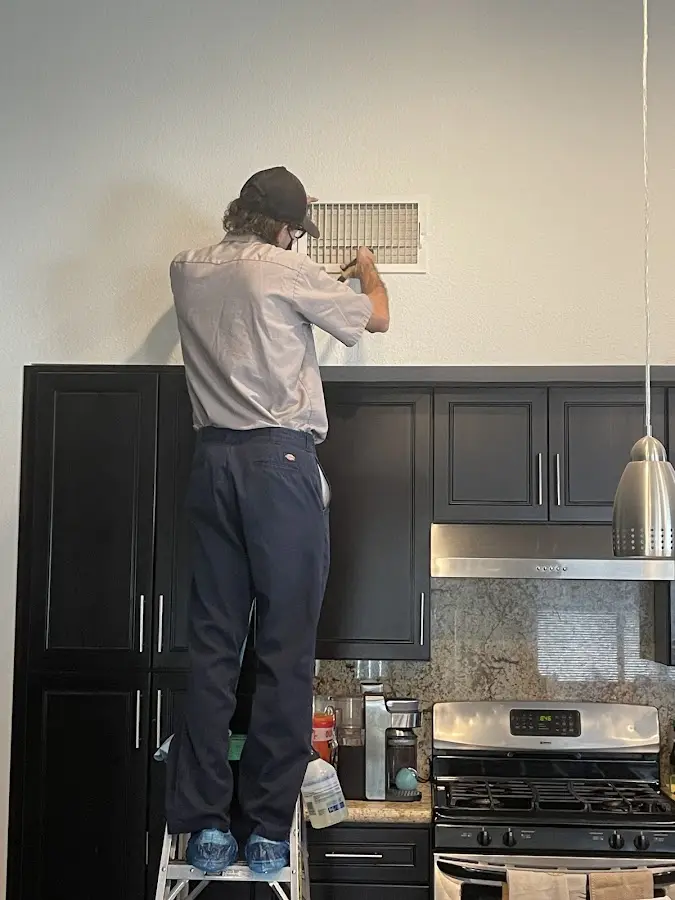 Technician inspecting an air vent during HVAC service in Enterprise
